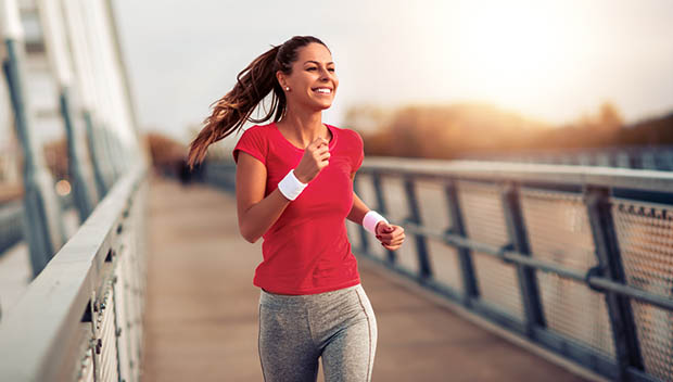 Beautiful fit woman in good shape jogging alone on city bridge.